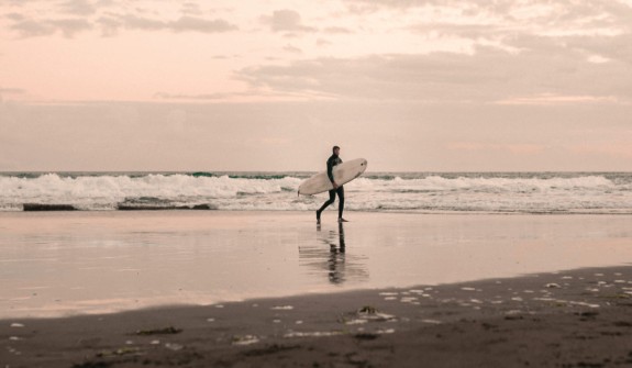 Surfer walking from surf at dusk